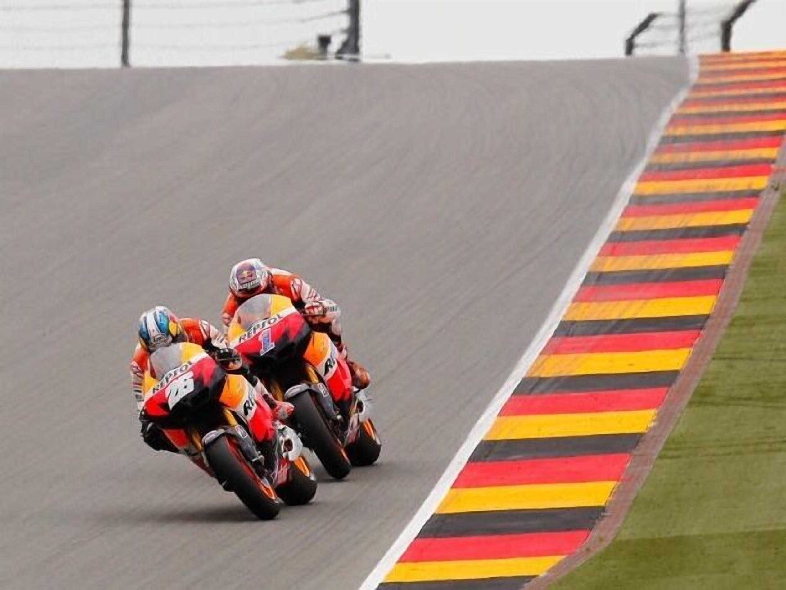 A motorcycle race on a track with a curb painted in red, yellow, and black stripes.