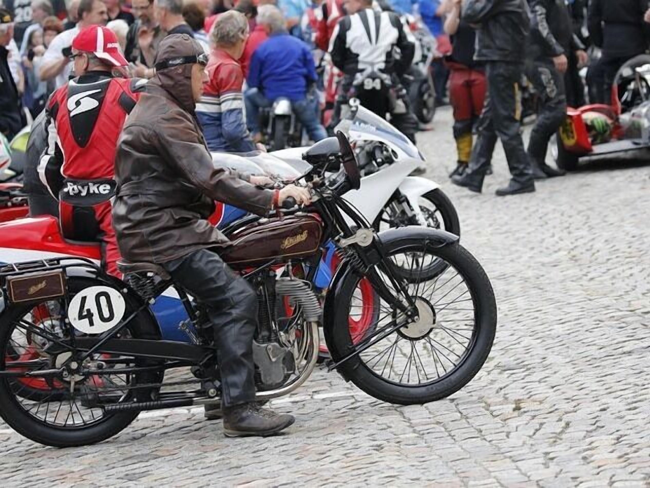 A vintage motorcycle with a number 40 on the back, ridden by a person in a leather jacket.