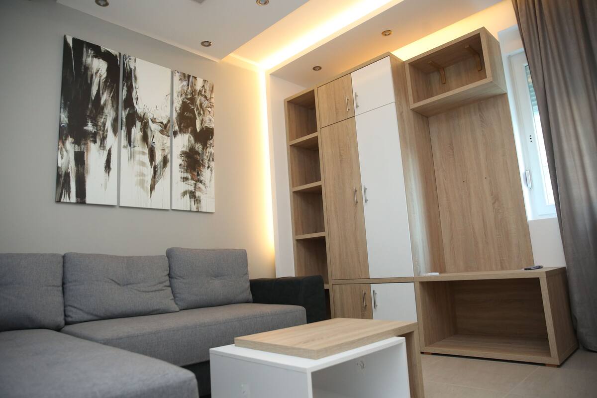 A modern living room with a grey sectional sofa, a wooden coffee table, and a large abstract painting on the wall.