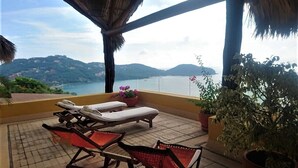 A terrace with lounge chairs and a table, overlooking a body of water and hills. - Spectacular luxury penthouse at La Ropa beach, unique view, private rooftop pool (Playa la Ropa)