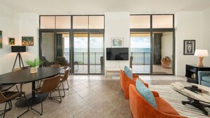 A modern living room with a dining area, large sliding glass doors leading to a balcony with a view of the ocean. - Exclusive Key West Beach Front - 2BR Luxury Condo w/Gym and Pool Access (Newly Refurnished!) (Key West)