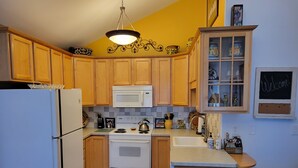 A kitchen with wooden cabinets, a white refrigerator, a stove, a microwave, and a sink.