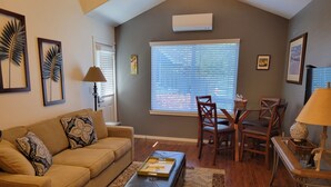 A living room with a sofa, coffee table, and a dining area with chairs and a table.