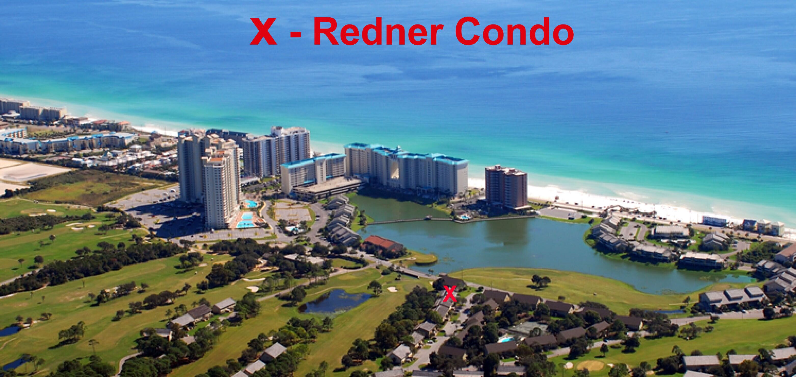 An aerial view of a coastal residential area with high-rise condos, a beach, and a body of water.