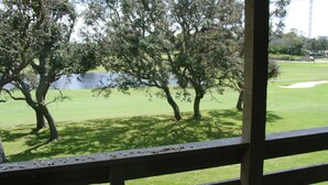 A view from a window with a wooden railing, overlooking a golf course with trees and a water body in the background. - SEASCAPE SUMMER SPECIAL/Golf Course Villa-2BR/LakeView/PET OK/Short Walk toBeach (Miramar Beach)
