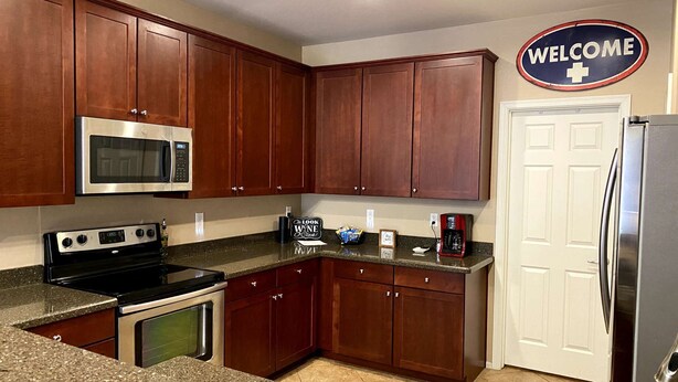 A kitchen with wooden cabinets, a stainless steel refrigerator, a microwave, and a coffee maker. - Beautiful 3bd/3ba Phoenix Home near Downtown Area, ASU! (Phoenix)