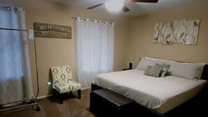 A bedroom with a bed, a chair, a ceiling fan, and a wall art piece. - Beautiful 3bd/3ba Phoenix Home near Downtown Area, ASU! (Phoenix)