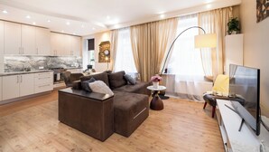 Una sala de estar moderna con un sofá seccional, un televisor de pantalla plana y una zona de comedor con encimera de mármol.