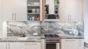 Una cocina moderna con armarios blancos, encimera de mármol, cocina a gas y horno.
