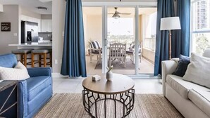 A modern living room with a sofa, a coffee table, and a balcony with a view. - Newly remodeled high-end beach front condo. Gulf view from every room on 8 acres (Destin)