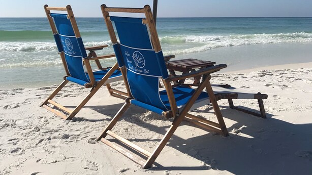 Two beach chairs under a blue umbrella on a sandy beach with footprints. - Newly remodeled high-end beach front condo. Gulf view from every room on 8 acres (Destin)