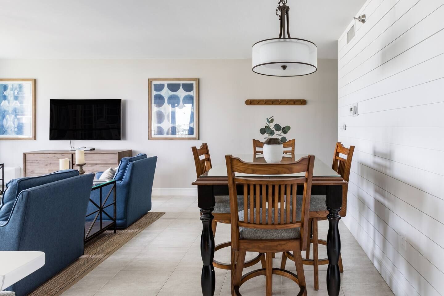 A dining area with a wooden table and chairs, a potted plant, and a modern pendant light.