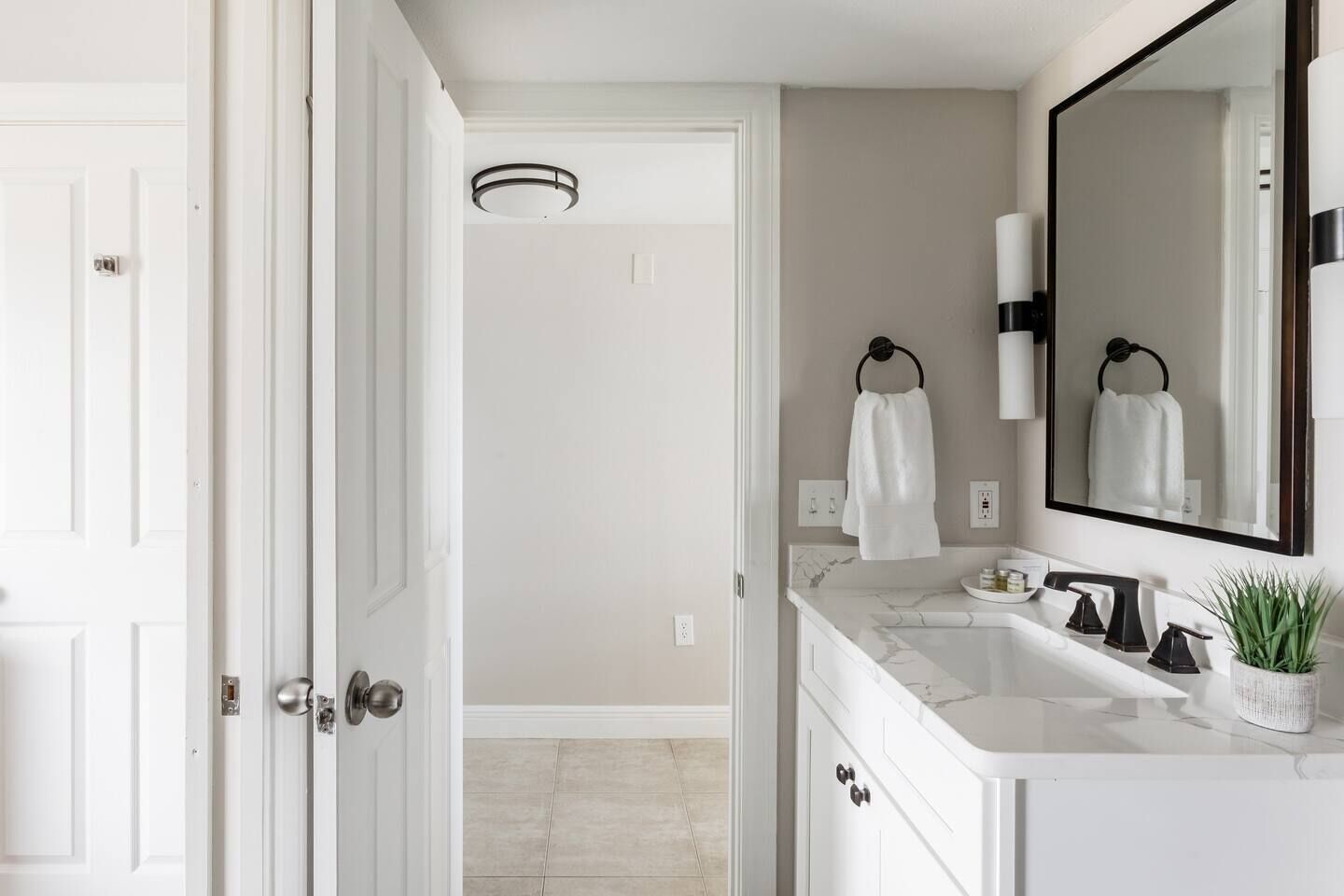 Une salle de bain avec un meuble-lavabo blanc, un grand miroir et deux porte-serviettes.