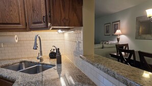 A kitchen with granite countertops, a double sink, wooden cabinets, and a tiled backsplash. - Home in Mechanicsburg, PA close to  Carlisle, Camp Hill, Enola, Harrisburg area (Mechanicsburg)