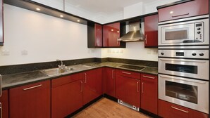 A modern kitchen with red cabinets, stainless steel appliances, and a granite countertop.