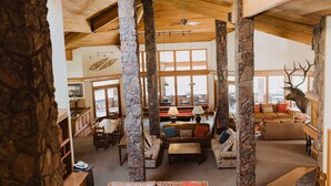 A spacious living area with stone pillars, wooden beams, and large windows. - The Ultimate Lodge for retreats, family reunions or Destination Weddings (Atlanta)
