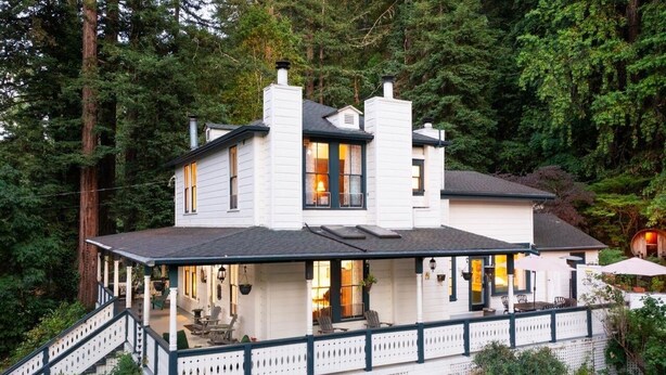 A white two-story house with a covered porch and a staircase leading to the entrance.