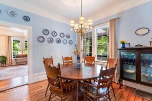 A dining room with a wooden table and chairs, a chandelier, and blue and white plates on the wall. - Relax by Russian River, spacious 6-bedroom retreat (Guerneville)