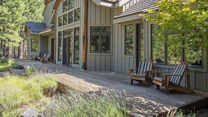 A wooden deck with Adirondack chairs, a wooden bench, and a view of a forested area. - LUXURY RUSTIC LODGE IN BLACK BUTTE RANCH (Black Butte Ranch)