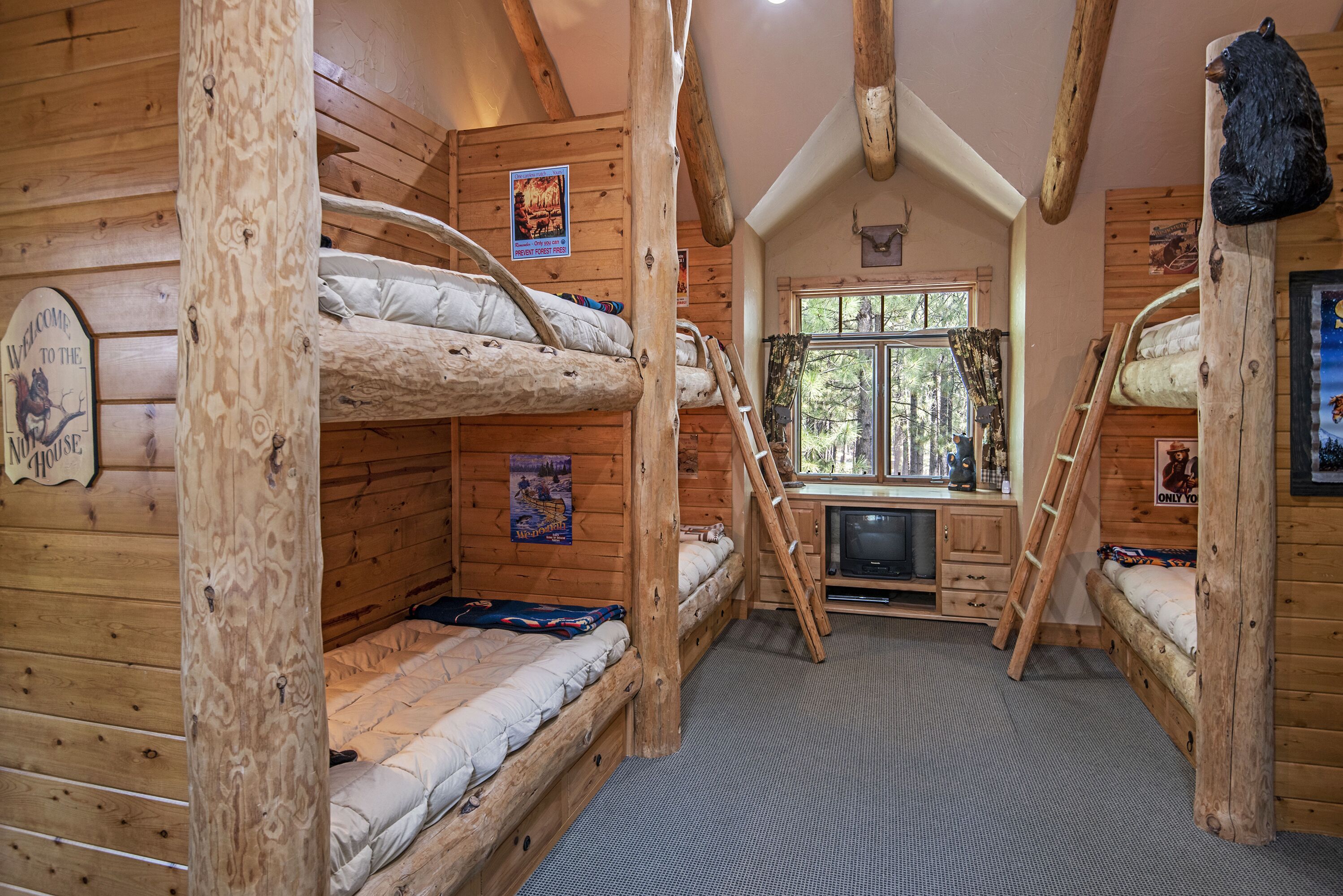A cabin with bunk beds, a TV, and a window with a forest view.