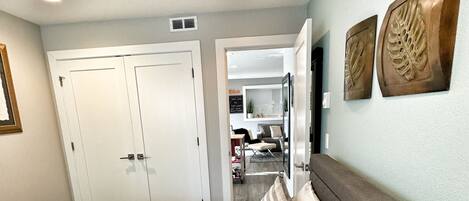 A hotel room with a large bed, a wardrobe, and a view into the living area.