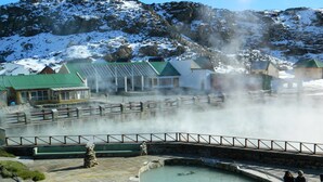 Ein Thermalbadbereich mit Pool, Steintreppe und Holzlattenzaun.