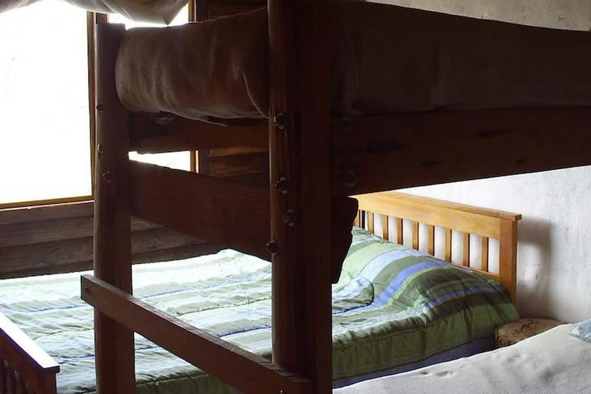 Dormitorio con literas, techo de madera y una ventana.