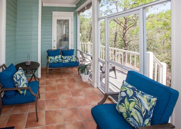 A covered porch with blue furniture and a potted plant.