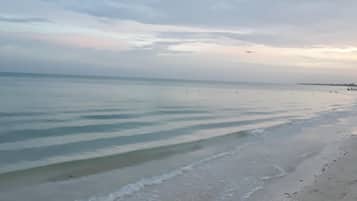 Een strand met rustig water en een bewolkte lucht.