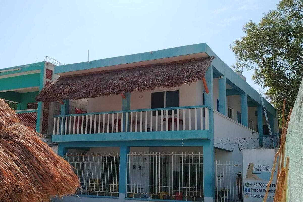 A two-story building with a blue and white color scheme, a balcony with a white railing, and a thatched roof.