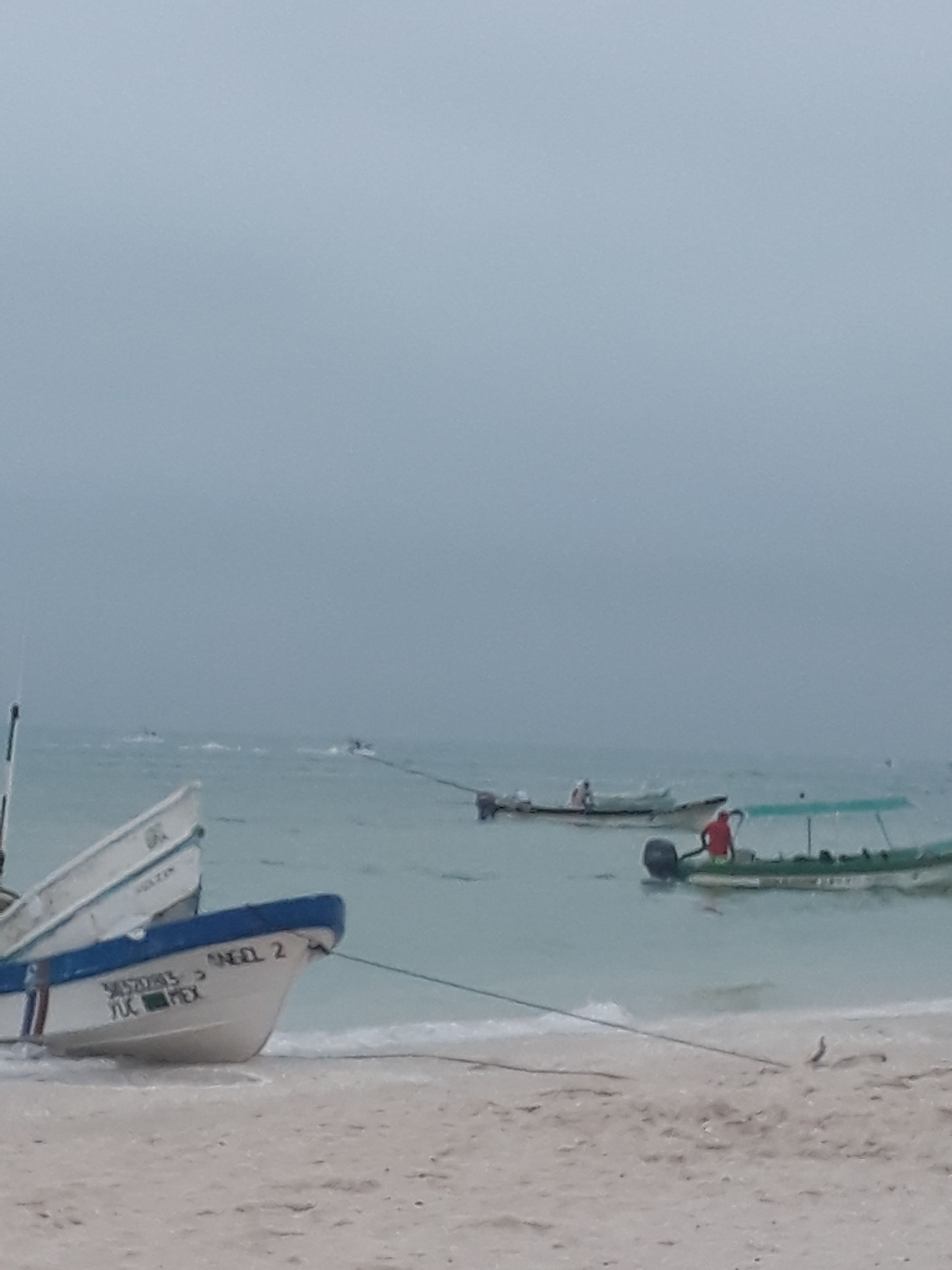 Ein Strand mit mehreren Booten, die im Wasser vor Anker liegen.
