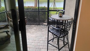Een balkon met een tafel en stoelen, uitzicht op een meer, en een statief met een camera.