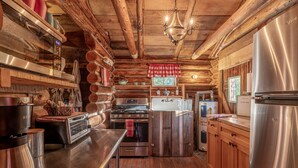 Una cocina rústica con paredes de madera, un refrigerador de acero inoxidable, una estufa y un lavamanos.