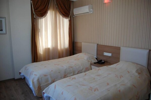 A hotel room with two beds, a headboard, an air conditioning unit, and a nightstand with a phone.
