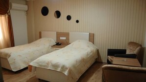 Una habitación de hotel con dos camas individuales, una mesita pequeña, una silla y un televisor de pared.