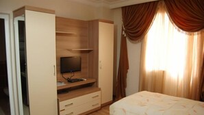 Un dormitorio con cama, televisor sobre un mueble de madera y armario.