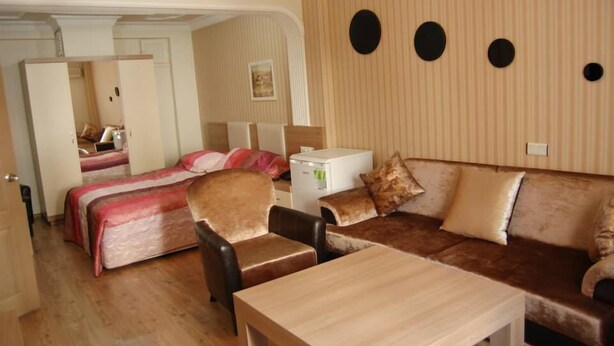 Habitación de hotel con cama, sofá, silla, mesa y escritorio pequeño con lámpara.