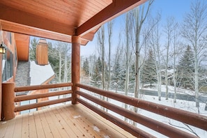 Ein hölzerner Balkon mit Blick auf schneebedeckte Bäume und einen klaren Himmel.