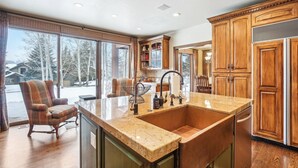 A kitchen with a large island, wooden cabinets, and a view of a snowy landscape.
