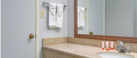 Un baño con encimera de granito, un espejo y un perchero para toallas.