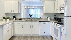 A modern kitchen with white cabinetry, a dishwasher, a refrigerator, and a built-in oven. - Family Paradise w/ Pvt Pool, BBQ Grill, Themed Bedrooms, Game Room & Club access (Kissimmee)