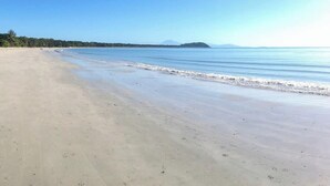 A beach with a clear sky, calm water, and distant landforms. - Villa Del Mar - Beachfront Port Douglas (Port Douglas)