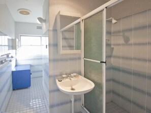 Een badkamer met een wit wastafel, een spiegel en een douchecabine.