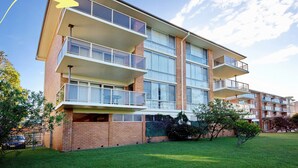 A multi-story residential building with balconies, a brick facade, and a grassy front yard. - Shoalhaven 6 with Stunning Ocean Views (Nelson Bay)