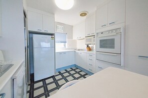 A compact kitchen with white cabinets, a refrigerator, a microwave, and an oven.