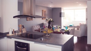A modern kitchen with a central island, built-in oven, and a dining area with a view of the outdoors. - Family_ friendly (Cuenca)
