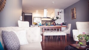 A modern living room with a white sofa, a dining table with chairs, and a kitchen in the background. - Family_ friendly (Cuenca)