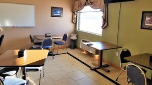 A classroom with a whiteboard, a TV mounted on the wall, and a window with curtains. - Abby Inn (Abbotsford)
