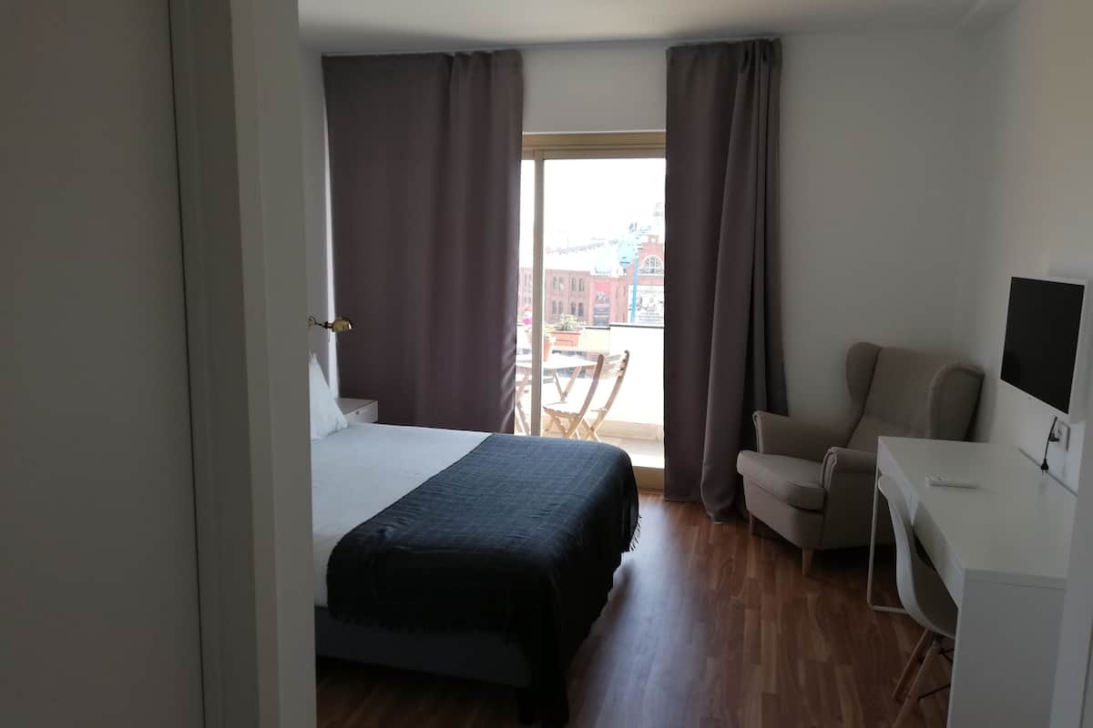 A hotel room with a bed, a desk, a chair, and a TV.