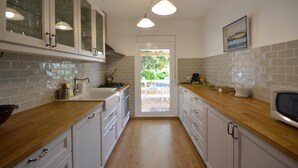 A kitchen with white cabinets, a wooden countertop, a sink, and a microwave. - Holiday rental townhouse with swimming pool in Begur, Centre (Begur)